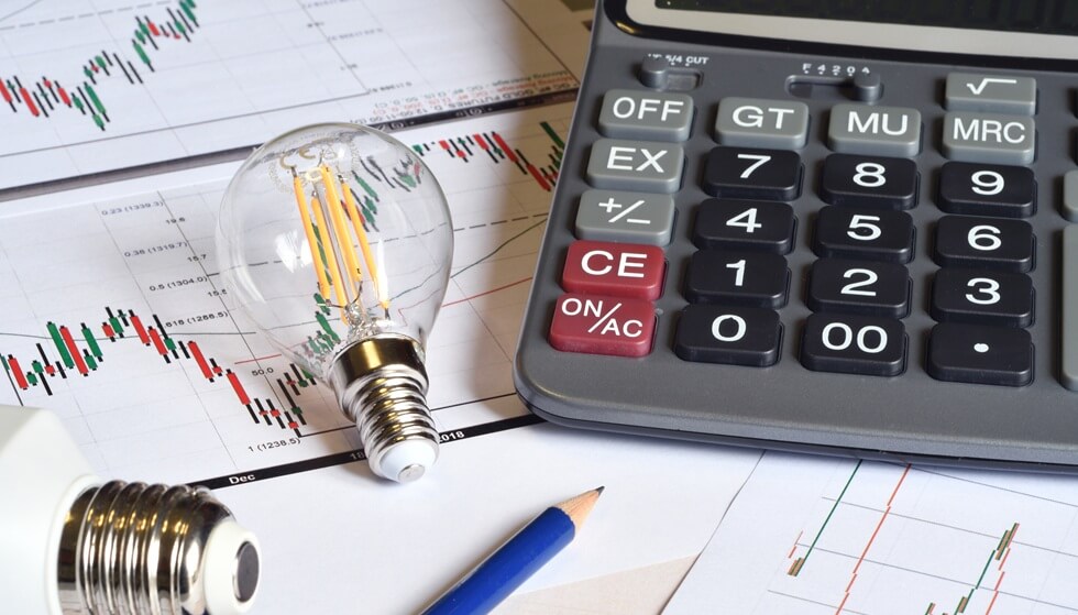 close up of energy saving light bulbs, calculator and pencil on printed graph