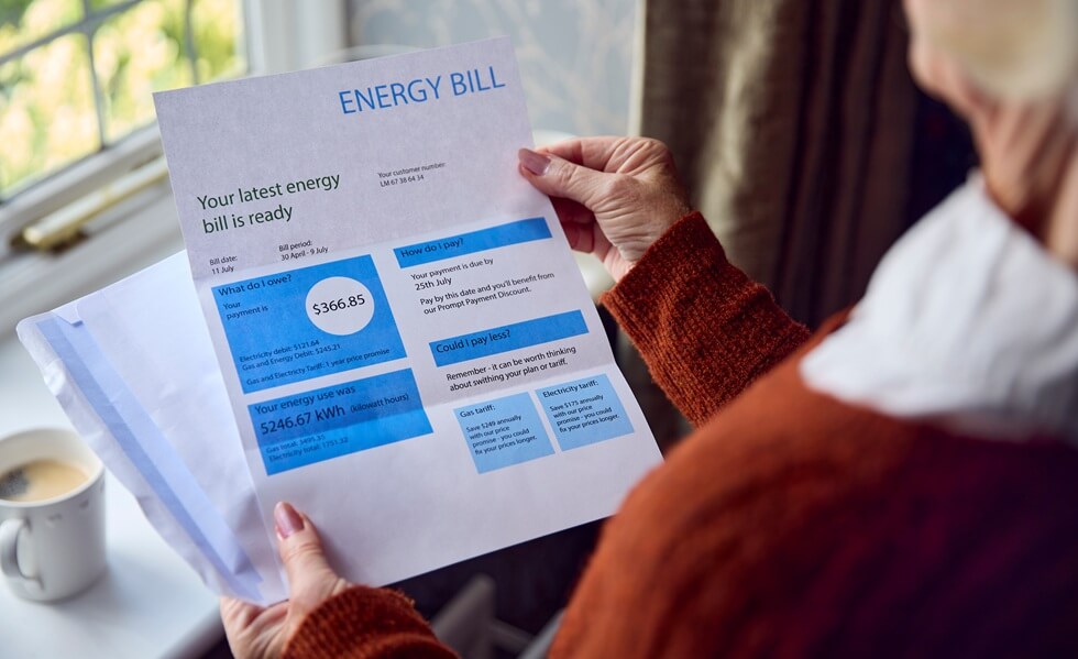 close up of senior woman opening monthly electricity bill concerned about cost of living energy crisis