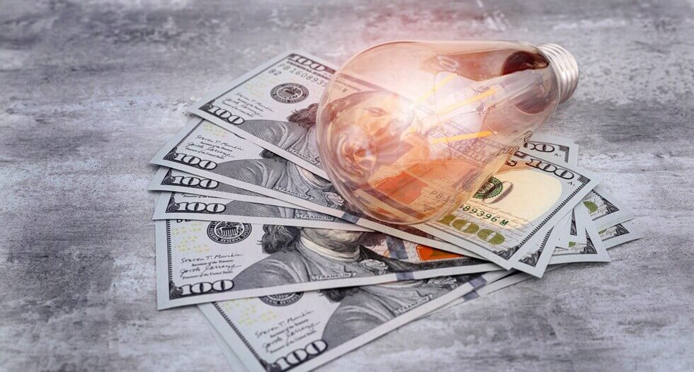 light bulb on $100 bills to represent monthly electricity bill