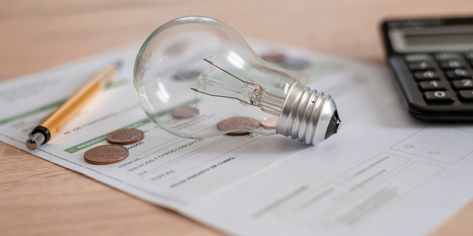 monthly electricity bill with light bulb, several coins, calculator and pen on the desk