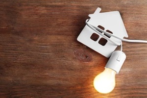 bulb and shape of home on wooden background