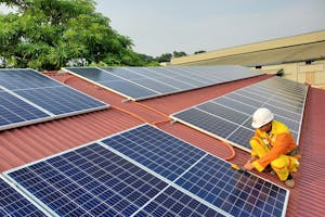 Technician Installing Solar Panels at Roof