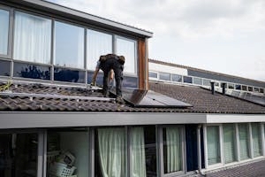Technician Installing Solar Panel on Modern Building Rooftop