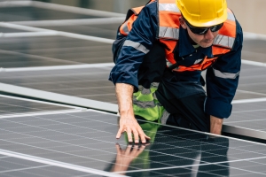 Technician Installing Solar Panels on Commercial Building Rooftop