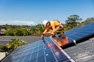 Expert Technician Installing Solar Panels with Drill on House Roof