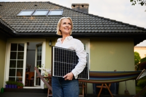 Woman Standing with Solar Panel Outdoors at Backyard of Her House