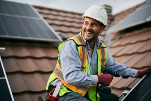 Smiling Worker Mounting Solar System on Roof of Residential Building