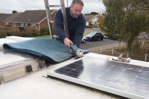 Local Worker Removing Old Solar Panels from Rooftop